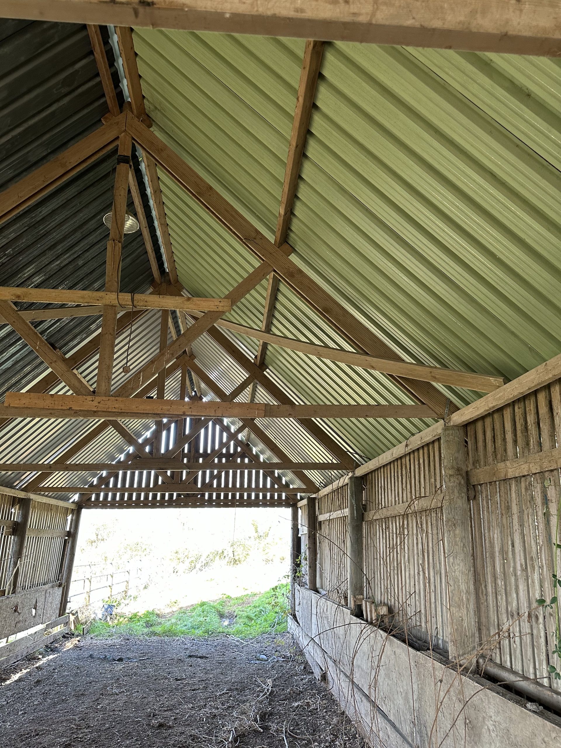 Andrews Farm barn: side elevation viewed across the field, dark timber cladding and corrugated metal roof