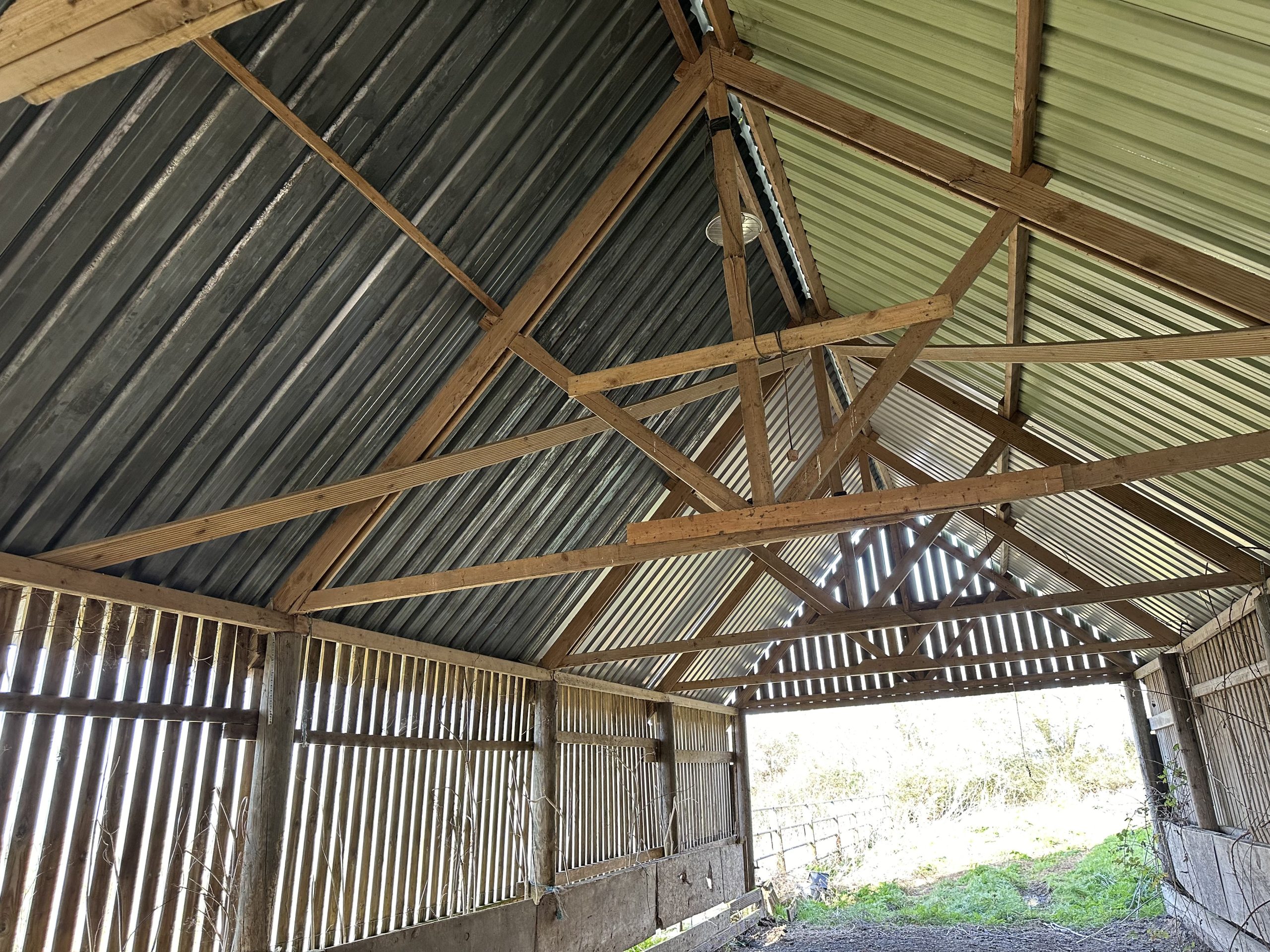 Andrews Farm barn interior: looking along the length of the barn, straw bales on the earth floor, open countryside visible through the far end